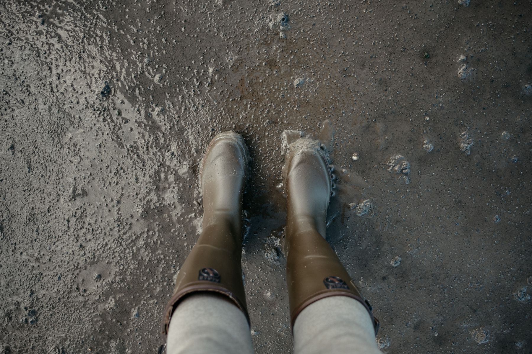 Blick von oben auf Gummistiefel im Watt